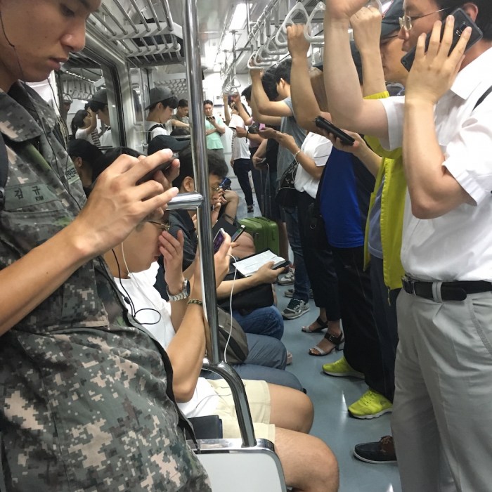 In a subway car in Seoul, nearly everyone is one a mobile device, except for one man who is reading a Bible