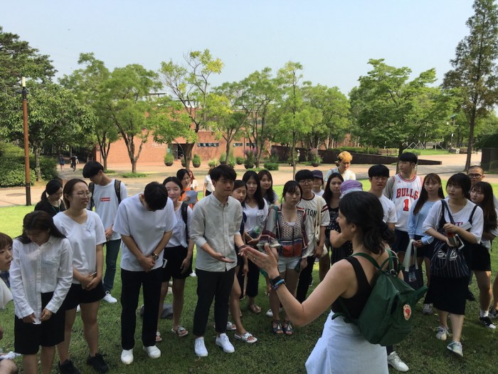 Deborah Zlotsky speaks to a group of Samsung Art and Design Institute students in the shade of a tree, Seonyudo Park, Seoul, South Korea
