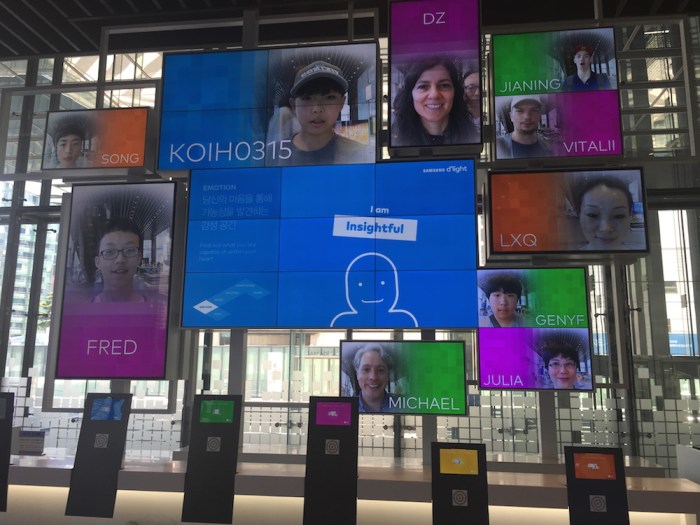 A wall of screens at the Samsung D-light Store, Seoul, South Korea, shows names and faces of visitors, including Deborah and Michael